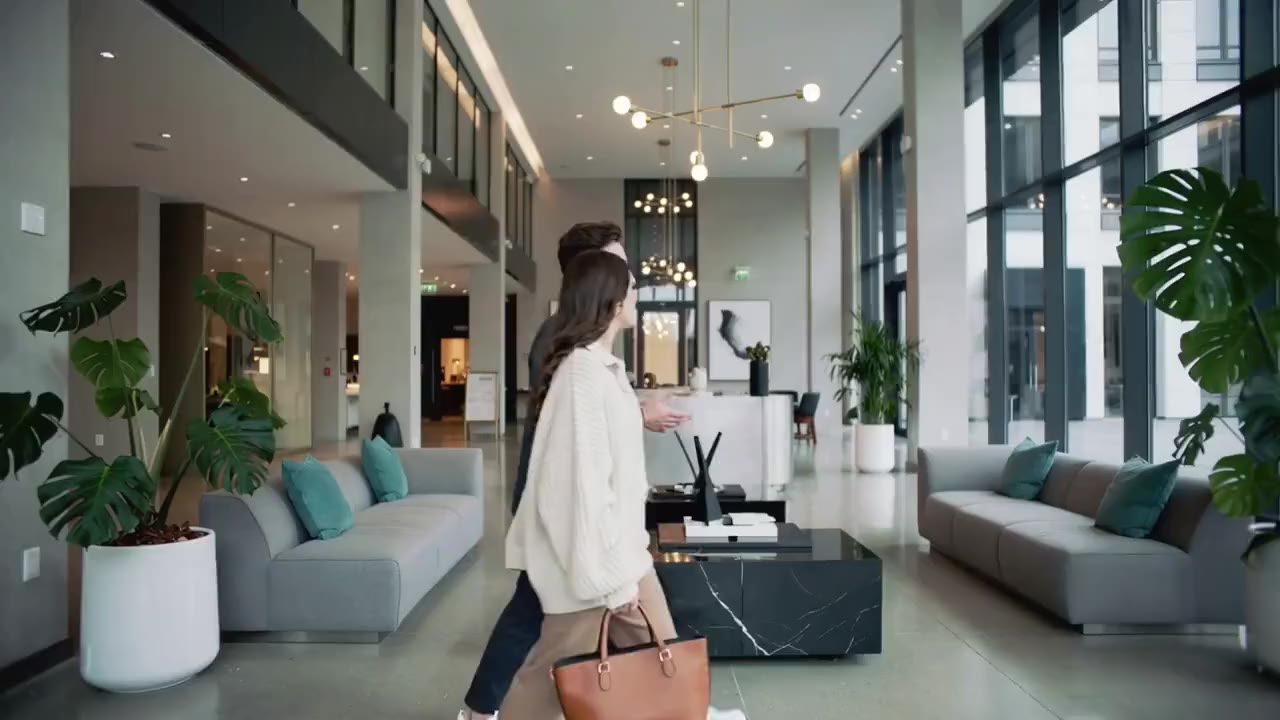 A bright, modern hotel lobby with a guest arriving at reception.